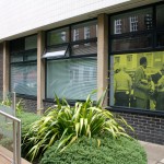 Photograph of the Museum Studies building with one of the 100 Images printed onto one of the windows