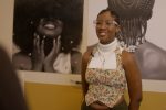 Zhara Elizabeth with her artwork Hidden in our Hair, displayed in the community gallery space at the Migration Museum in Lewisham, London. Photography by Felix Ursell.